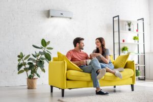couple-sitting-on-couch-ductless-system-in-background